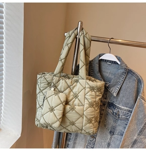 Close-up of olive green quilted tote bag featuring floral embroidery and small side pouch