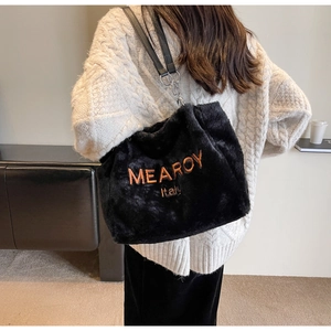 Detail of plush black faux fur tote with orange embroidery and leather chain strap