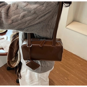 Close-up of deep brown minimalist box bag with adjustable strap and mini coin purse