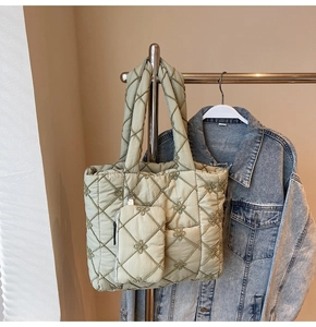 Detail of light green quilted tote bag with floral embroidery and mini pouch attachment