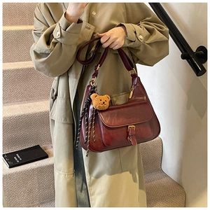 Détail du sac à bandoulière vintage en cuir bordeaux avec boucle et breloque ours peluche