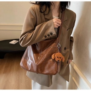 Detail of brown faux leather tote bag with a cute plush teddy bear charm on shoulder strap