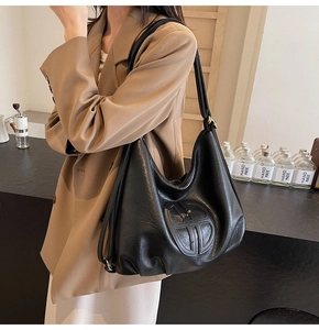 Detail of soft black leather shoulder bag showing the embossed logo and retro texture