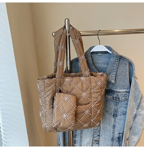Detail of brown quilted tote bag featuring floral embroidery and matching pouch attachment