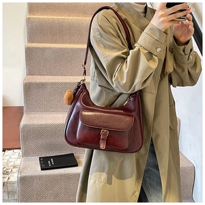 Sac à bandoulière bordeaux rétro avec texture cirée et pompon sur le mannequin