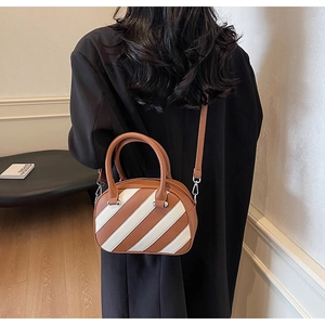 Borsa bowling bicolore marrone e bianca con trama litchi indossata da una modella