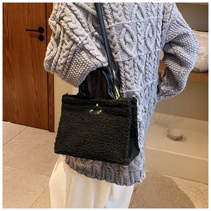 Detail of black fuzzy faux fur tote bag showing plush texture and gold metal buckle