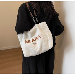 Detail of white faux fur tote with brown letter embroidery and silver chain strap