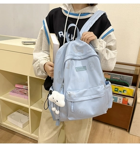 Close-up of light blue backpack with cartoon rabbit prints and white plush cloud charm