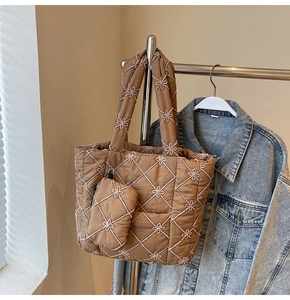 Macro detail of brown quilted tote bag with white flower embroidery and matching charm