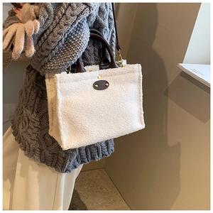 Detail of white plush tote bag showing leather handle and adjustable shoulder strap
