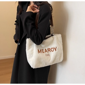 Detailed view of the soft plush tote bag with brown embroidery and dark leather handle