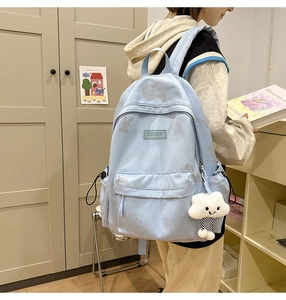 Detail view of light blue student backpack with cartoon prints and plush cloud charm