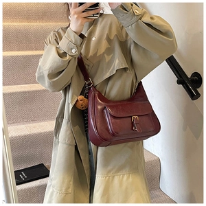 Détail du sac hobo bordeaux avec poche à boucle dorée et breloque ourson brun