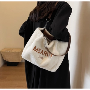 Detail of white plush tote bag featuring brown embroidery and premium leather strap