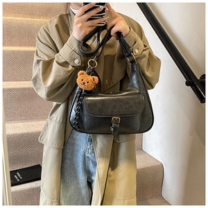 Détail du sac à bandoulière rétro noir avec boucle en bronze vintage et breloque ourson