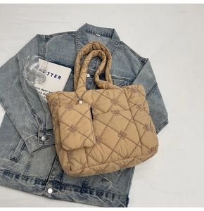 Detailed macro view of beige quilted tote bag with floral embroidery and small coin purse