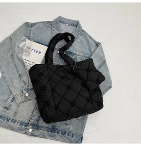 Close-up of black quilted tote bag with floral embroidery and matching mini pouch