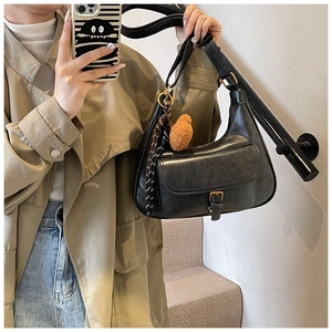 Détail du sac demi-lune noir vintage avec boucle dorée et accessoire en peluche