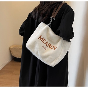 Detail of white plush tote bag with brown MEAROY embroidery and leather strap
