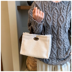 Detail of plush cream faux shearling tote bag with brown leather handles and oval label