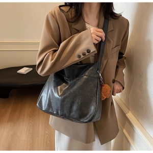 Detail of black faux leather tote with stitching and a brown plush bear charm