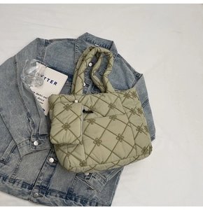 Detail of green quilted tote bag with floral stitching and matching zipper pouch charm