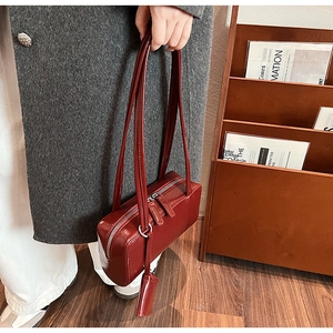 Detailed view of dark red leather shoulder bag styled in a cozy indoor street-style setting