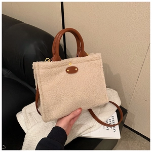 Detail of beige faux fur tote bag with brown leather handles and gold rivet oval patch