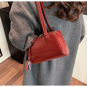 Detail of a dark red glossy underarm bag with a matching mini coin purse charm