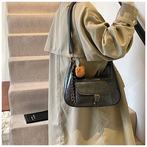 Détail du sac bandoulière en cuir vert foncé avec boucle vintage et porte-clé ours