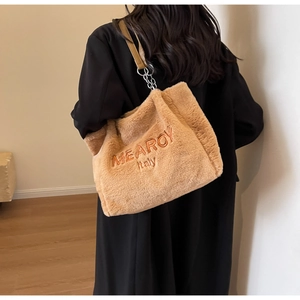 Detail of plush tote bag with MEARCY embroidery, leather strap, and metal chain