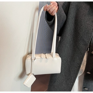 Close-up of white glossy shoulder bag with matching mini coin purse and double straps