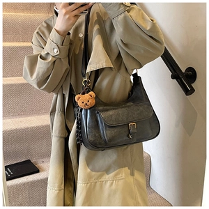 Détail d'un sac à bandoulière gris vintage avec boucle en métal et pendentif ours