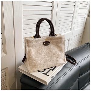 Detail of plush tote bag with brown leather handles and golden metal buttons on side