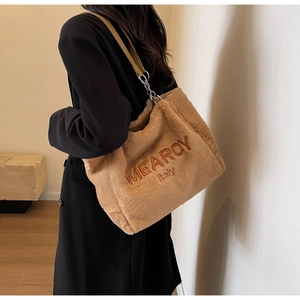 Detail of camel plush tote bag with brown embroidery showing capacity and texture