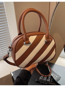 Borsa a mano bowling marrone con strisce bianche e texture litchi tenuta in mano