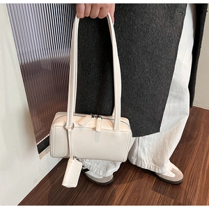 Detail of a minimalist cream white shoulder bag with dual zippers and smooth leather