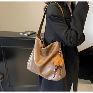 Detail of vintage brown leather hobo bag with a cute teddy dog plush charm on the strap