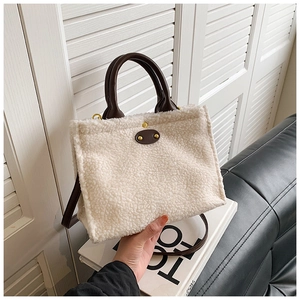 Detail of plush tote bag showing cream faux fur texture and brown leather strap