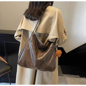 Detail of a large dark brown faux leather hobo bag with a cute teddy bear charm on shoulder