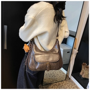 Vue détaillée du sac demi-lune marron rétro avec breloque ours et boucle en laiton