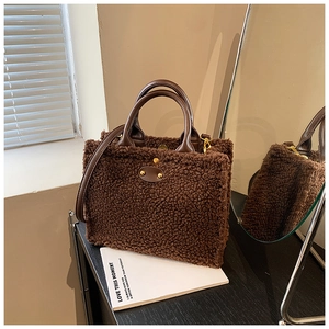 Detail of plush brown teddy fleece tote bag with leather handles and gold metal hardware