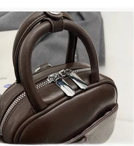 Détail de la double fermeture éclair argentée sur sac en cuir marron foncé élégant