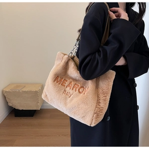 Detail of plush tote bag showing orange embroidery and faux fur texture on the shoulder strap