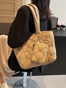 Beige quilted tote bag with floral embroidery and matching pouch in a casual street style
