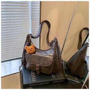 Détail du sac hobo marron foncé avec breloque peluche sur livre d'art vintage