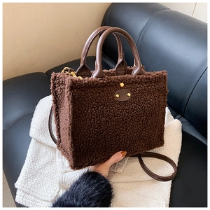 Detail of plush brown tote bag with leather handles and gold stud on knit background