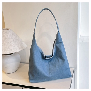 Détail du sac hobo en denim bleu clair avec coutures verticales et boucle en métal fine