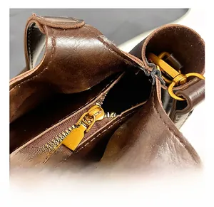 Detailed close-up of high-quality vintage bronze zipper and metal hardware on brown bag